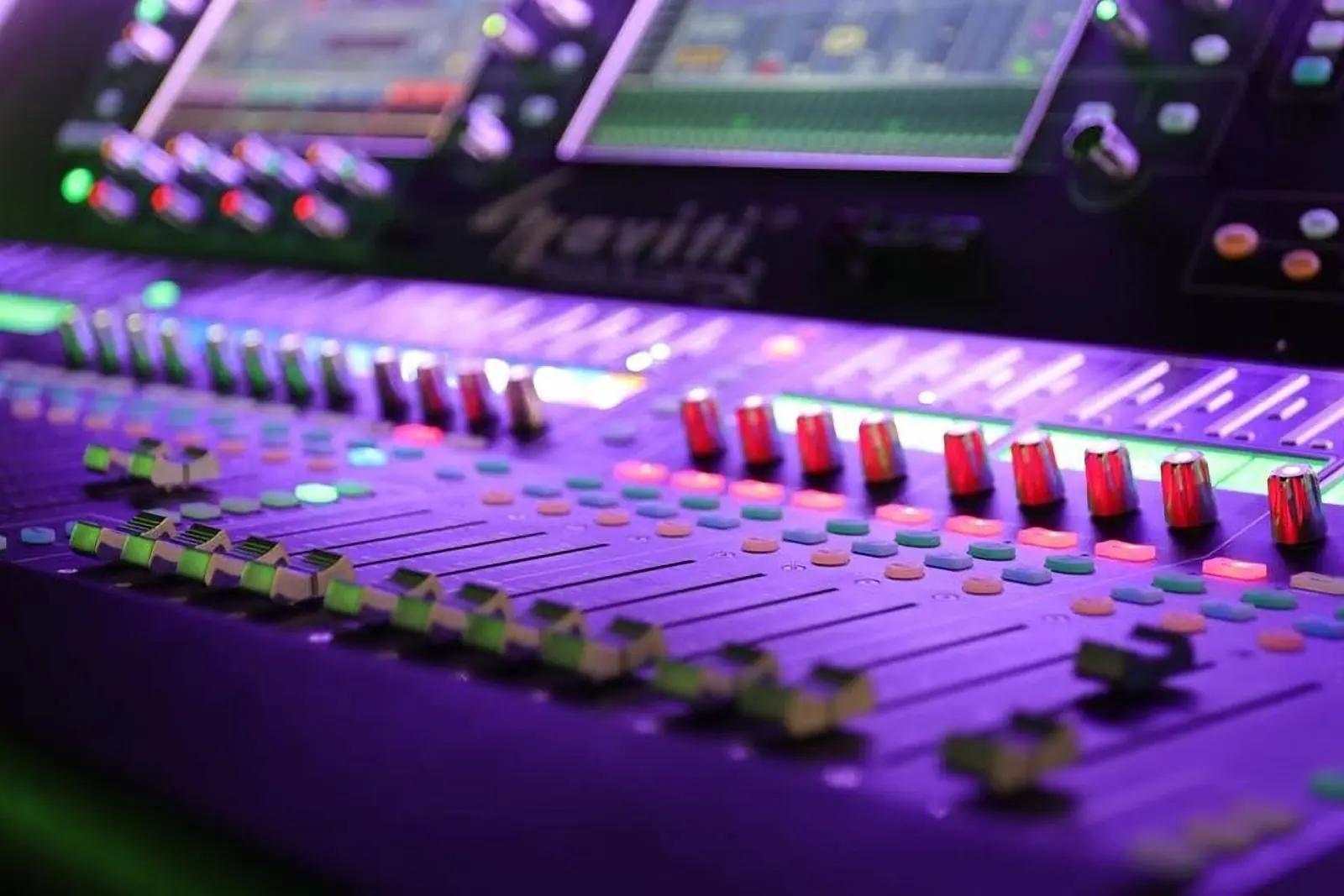 Digital mixing console glowing under stage lights during a live show