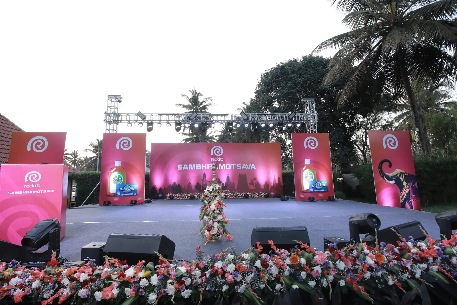 Outdoor Sambhramotsava stage with branded backdrops and a floral apron